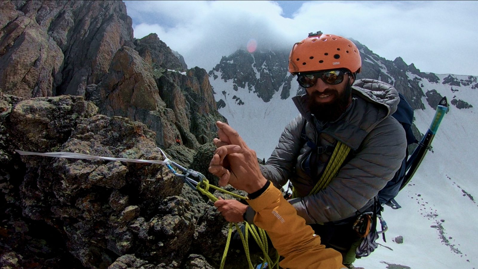 Alpine climbing in Svaneti — guide at a rope anchor high on the ridge