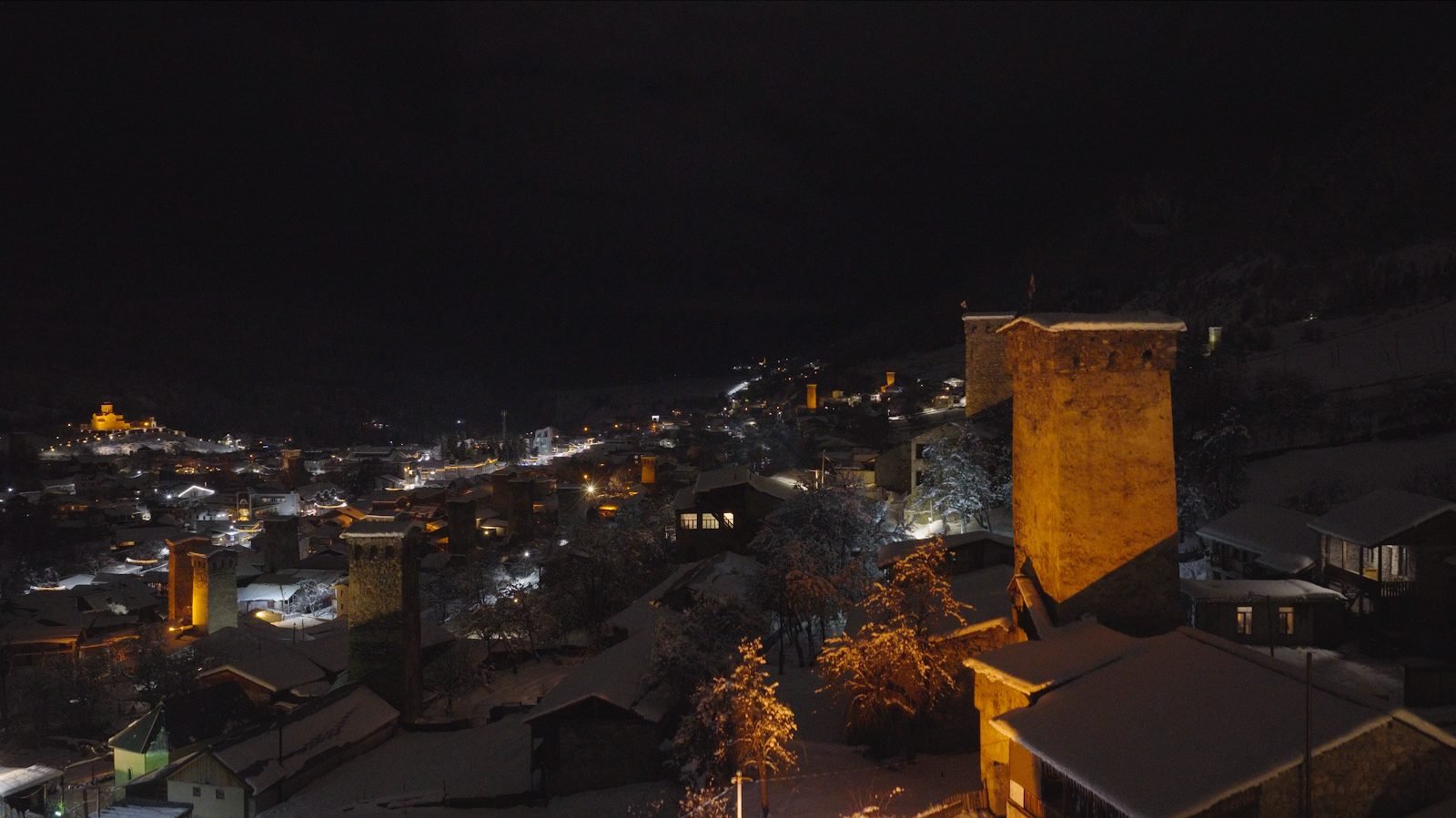 Illuminated stone tower above the town at night