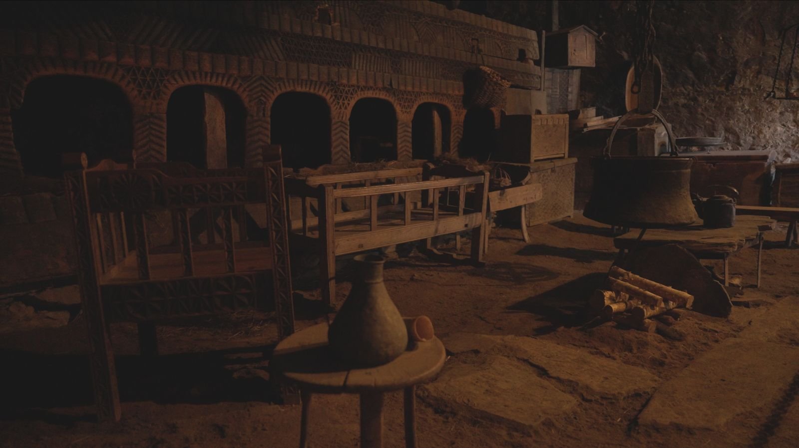 Traditional interior with a hearth and cooking vessels