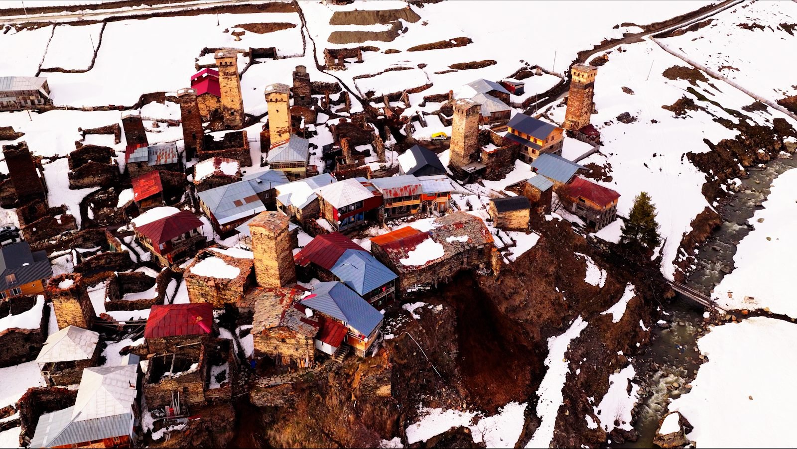 Vista aérea de casas-torre y un río en Ushguli