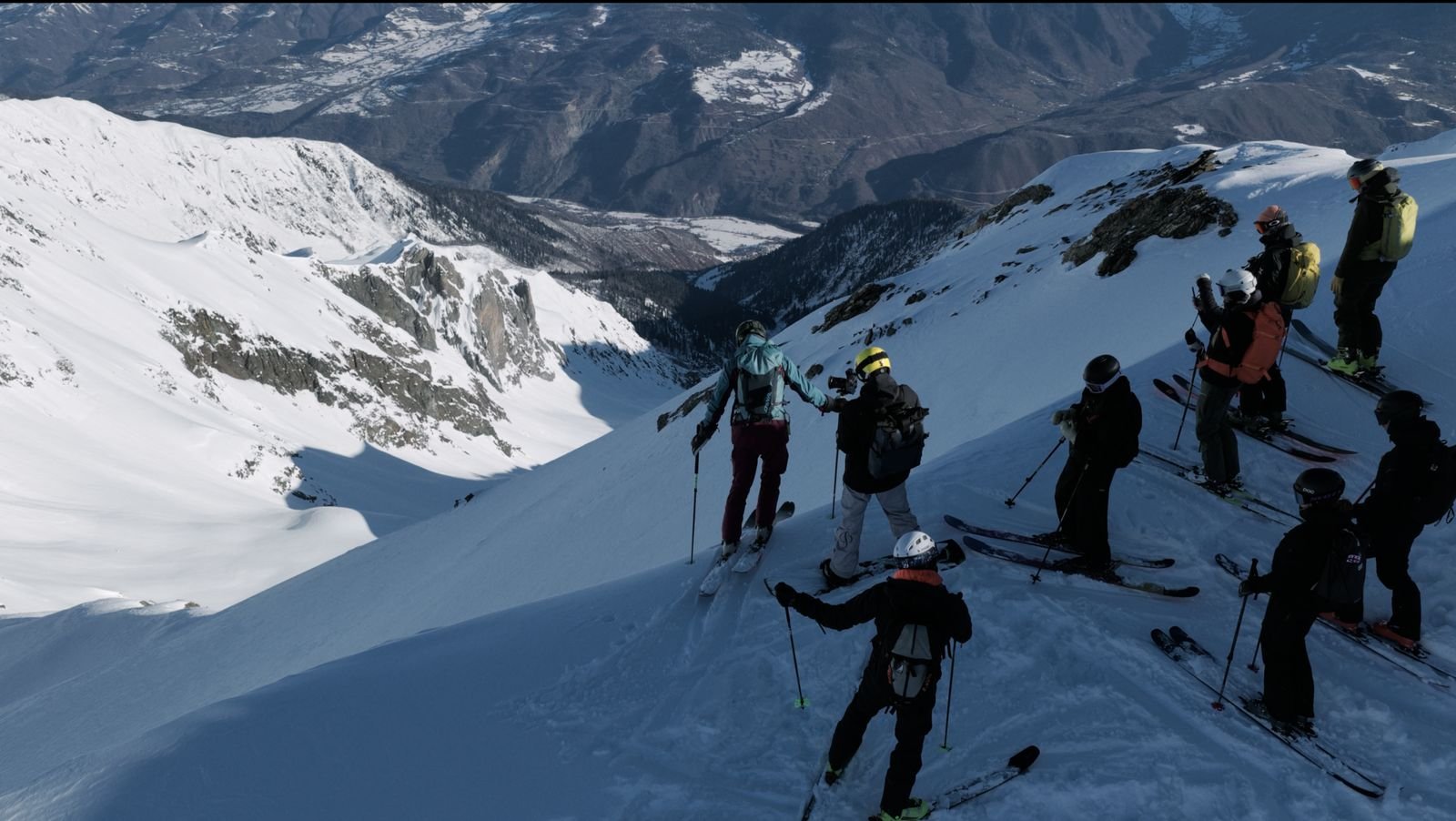 Guided freeride group standing at the top of a couloir high above a Svaneti valley