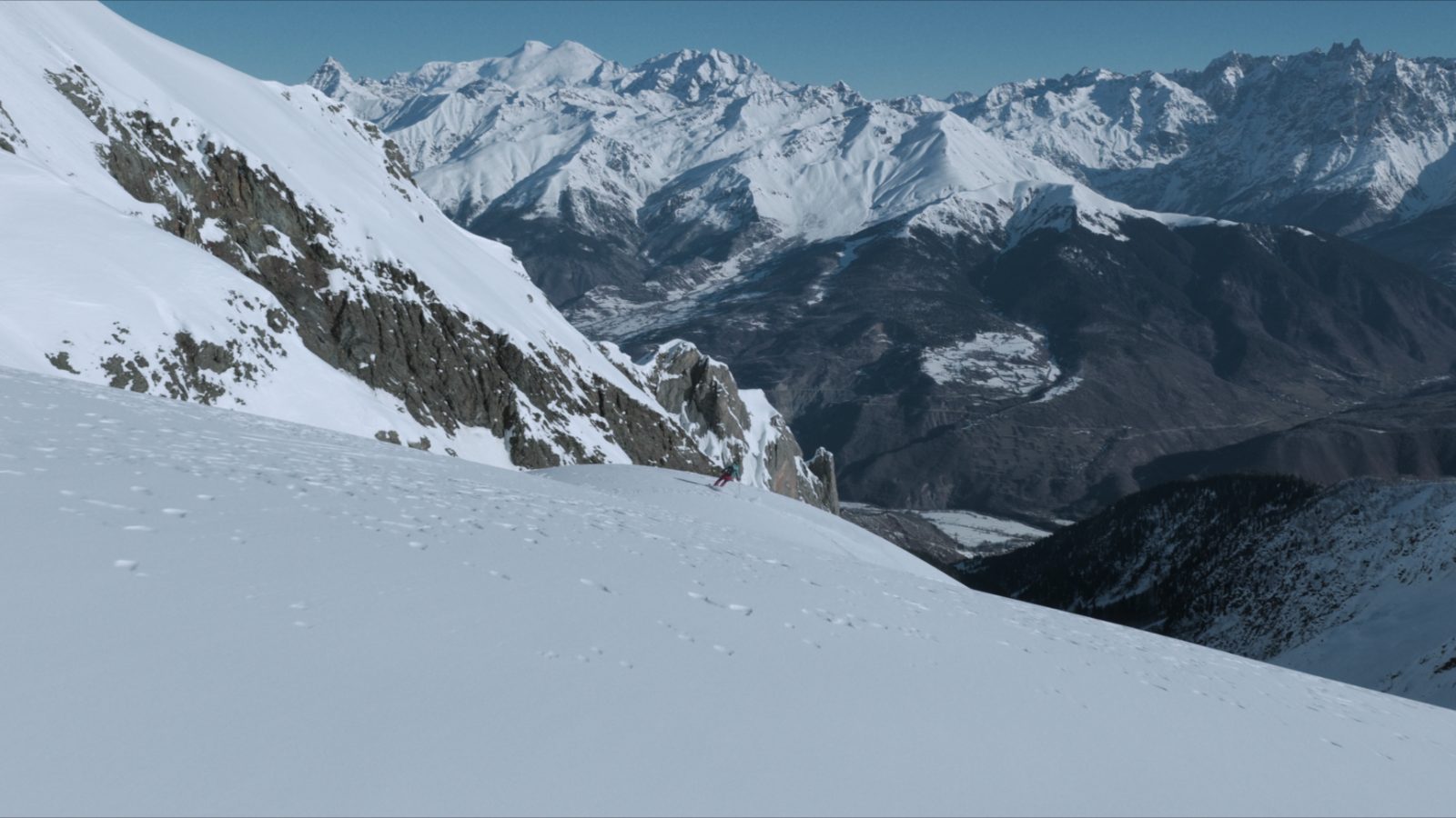 Guided freeride descent — skier dropping into a high bowl above Mestia