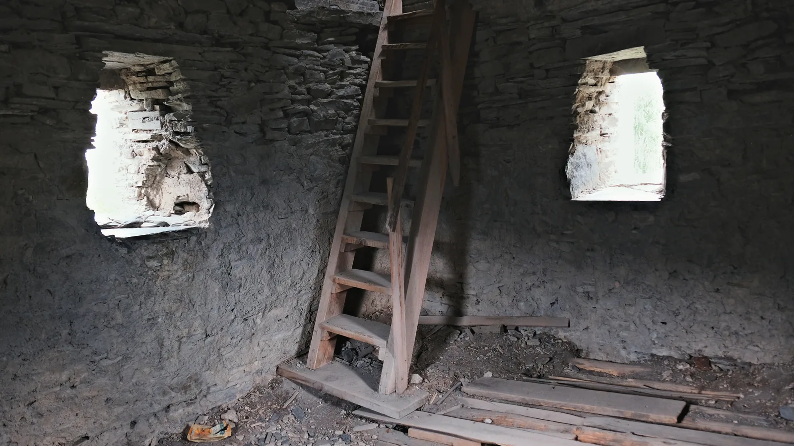 A wooden ladder and stone walls inside a Svan tower.