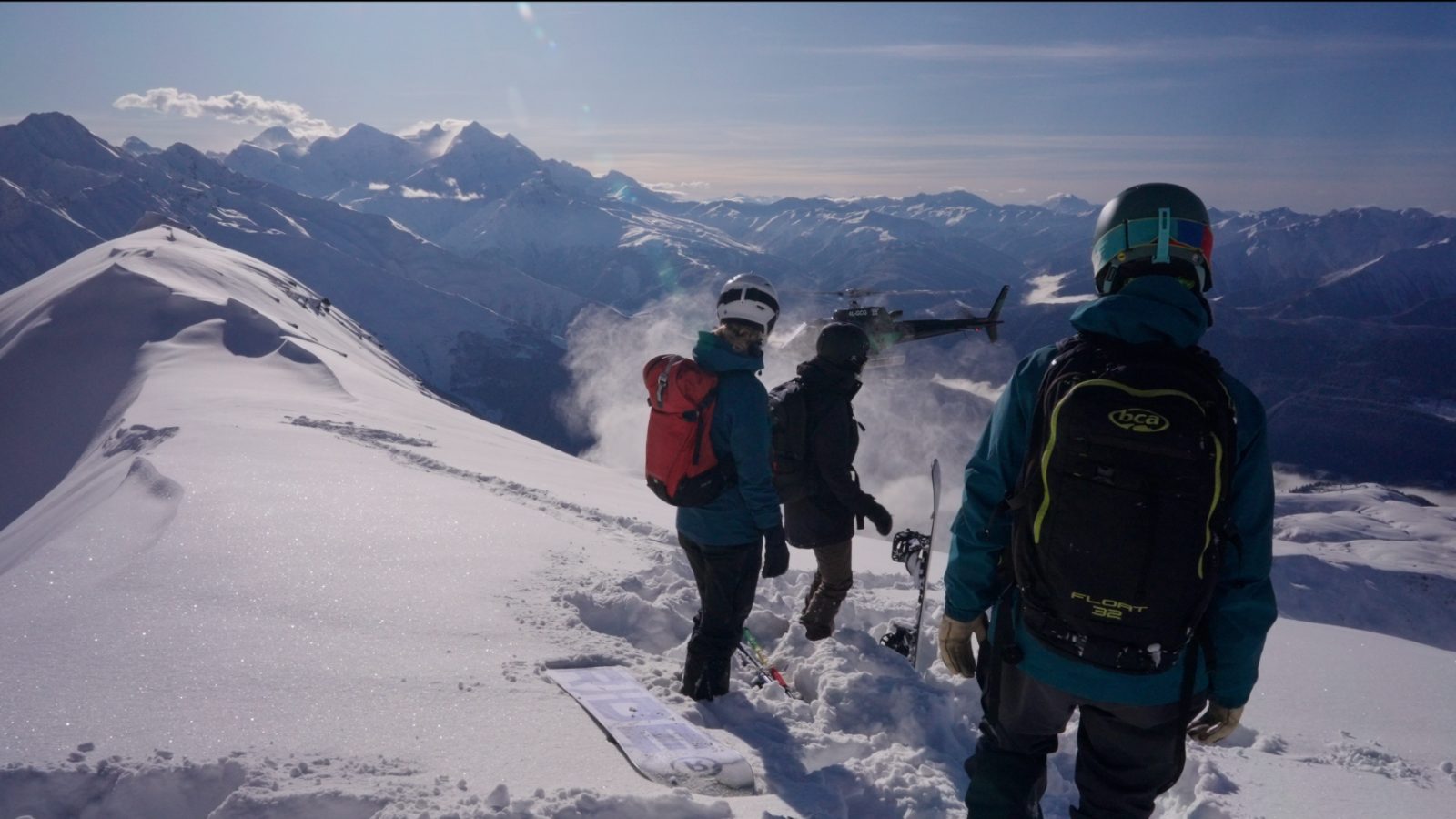 Heli-drop above Mestia — riders on the ridge as the helicopter comes in