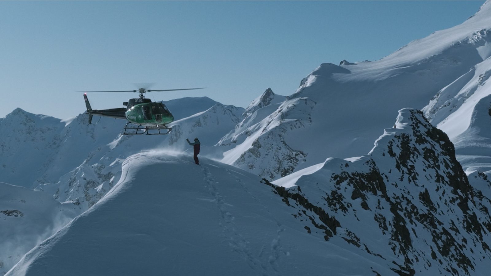 Heli-skiing in Georgia — snowboarders and guide waiting on a wind-blown ridge