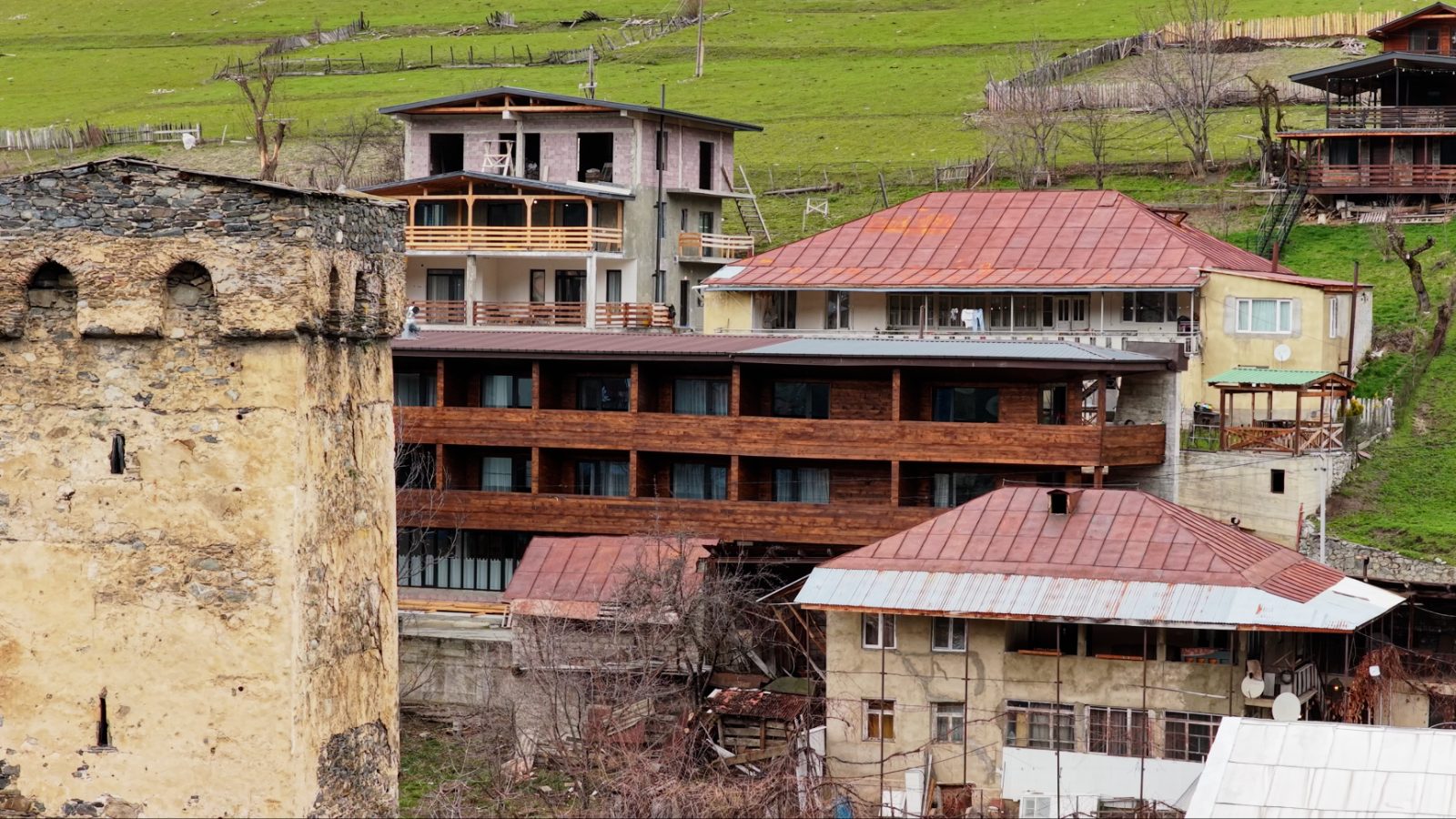 Timber hotel building beside a medieval Svan tower — Mestia
