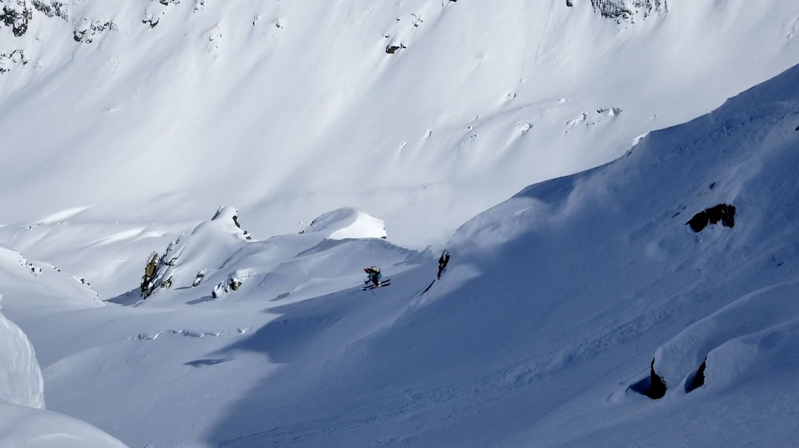 Two freeriders crossing a vast untouched snow bowl in the Svaneti backcountry