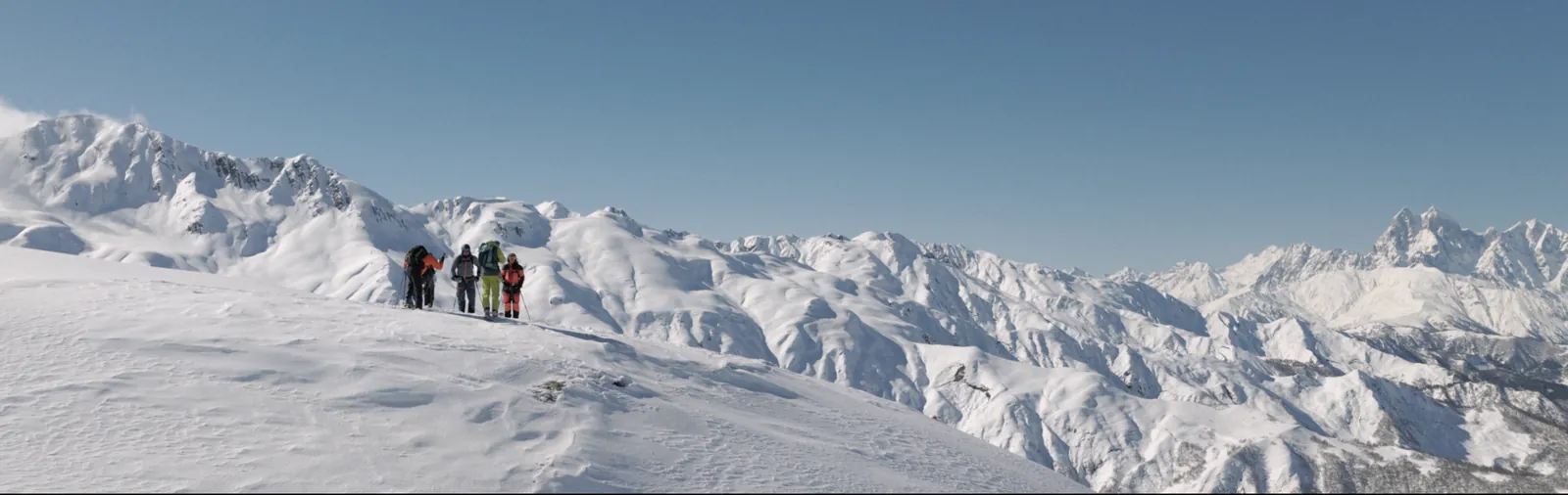 Ski expedition group on a high snowy ridge with Ushba on the horizon, Upper Svaneti