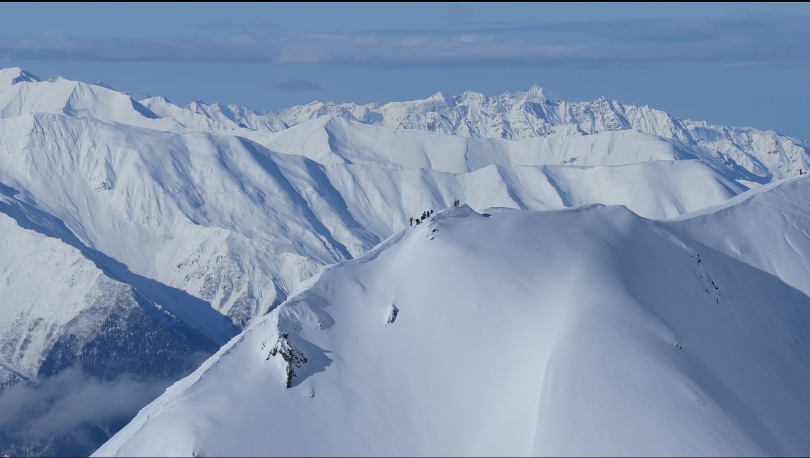 Group of ski tourers on a snow ridge high above Svaneti
