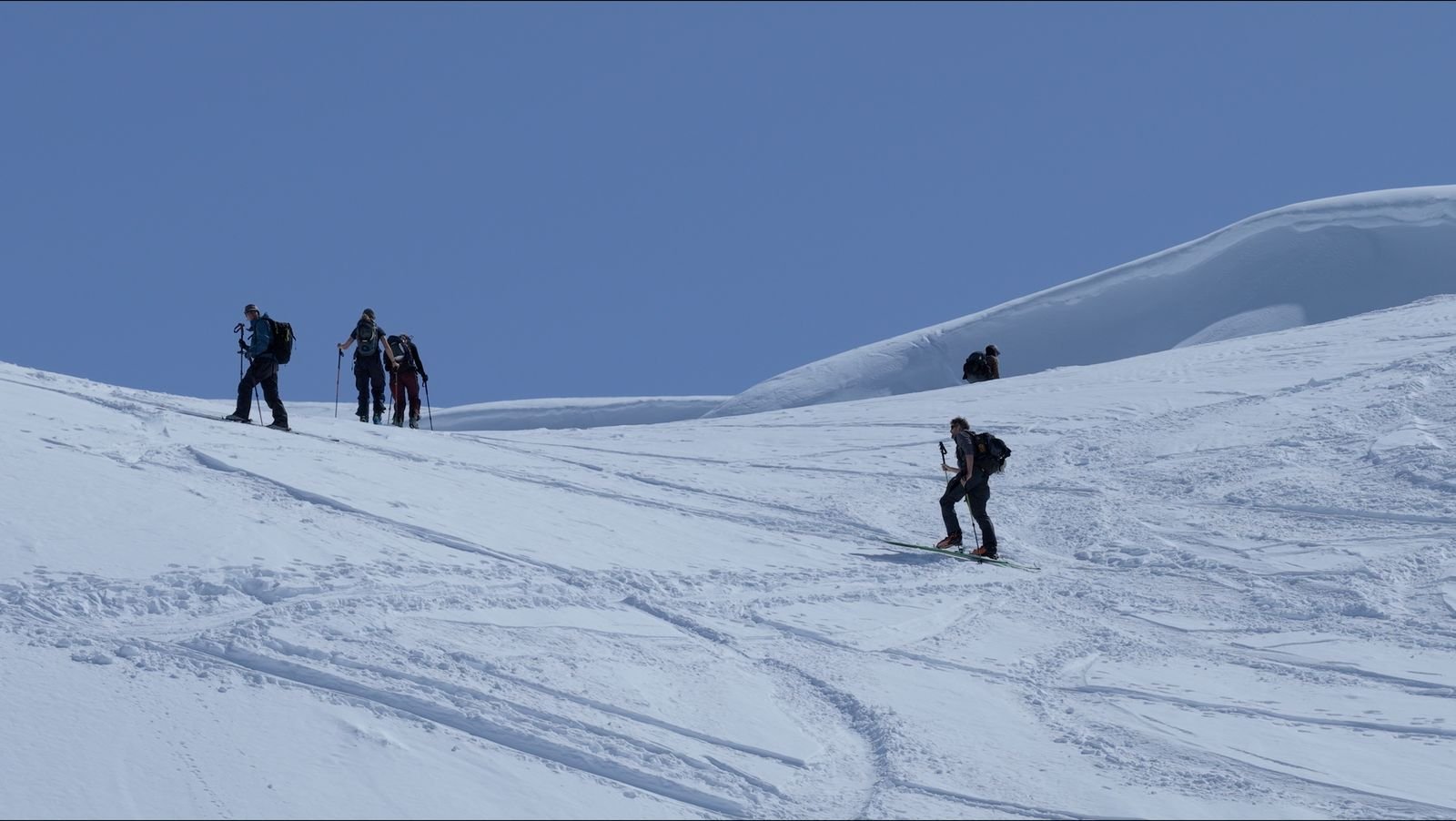 Skiers traversing below rocky ground