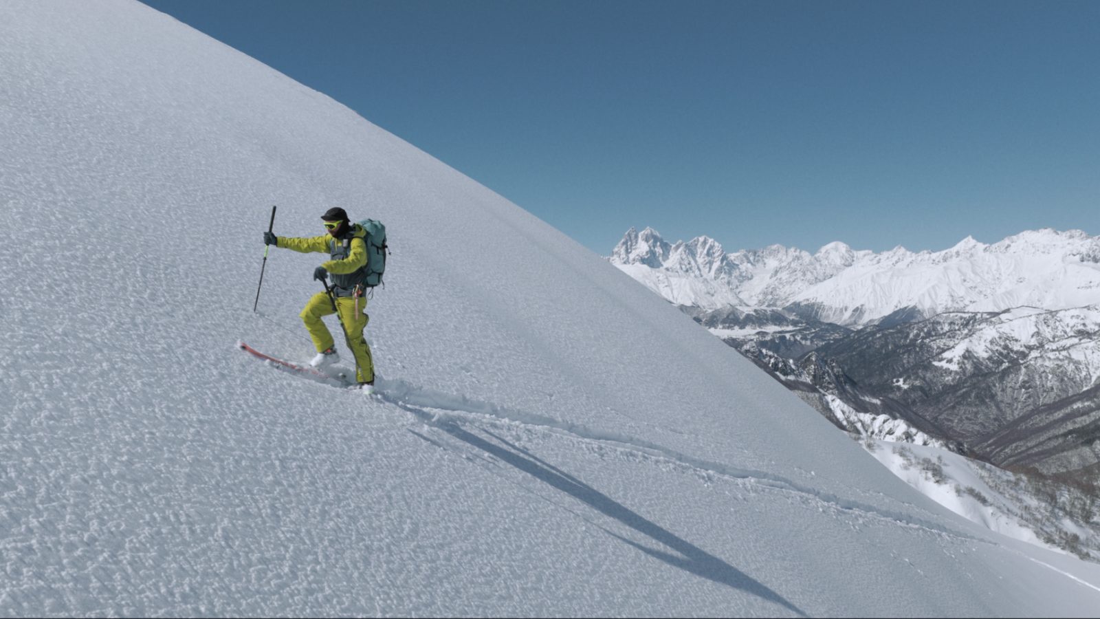 Ski touring in Svaneti — splitboarder walking the summit ridge into the sun