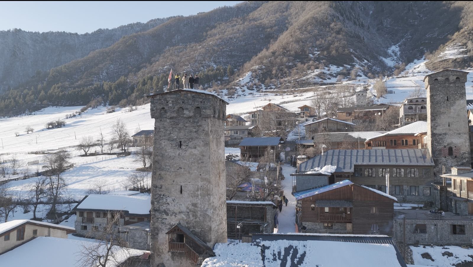 Group standing on top of a medieval Svan tower above a snowy village in Svaneti