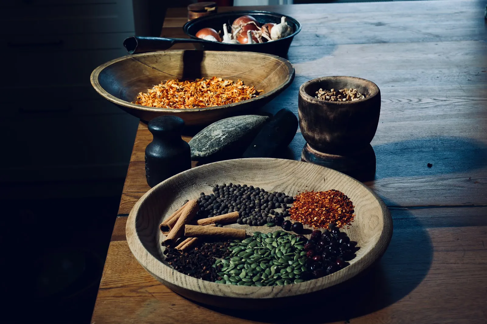 Spices, seeds and walnuts in wooden bowls on a rustic table