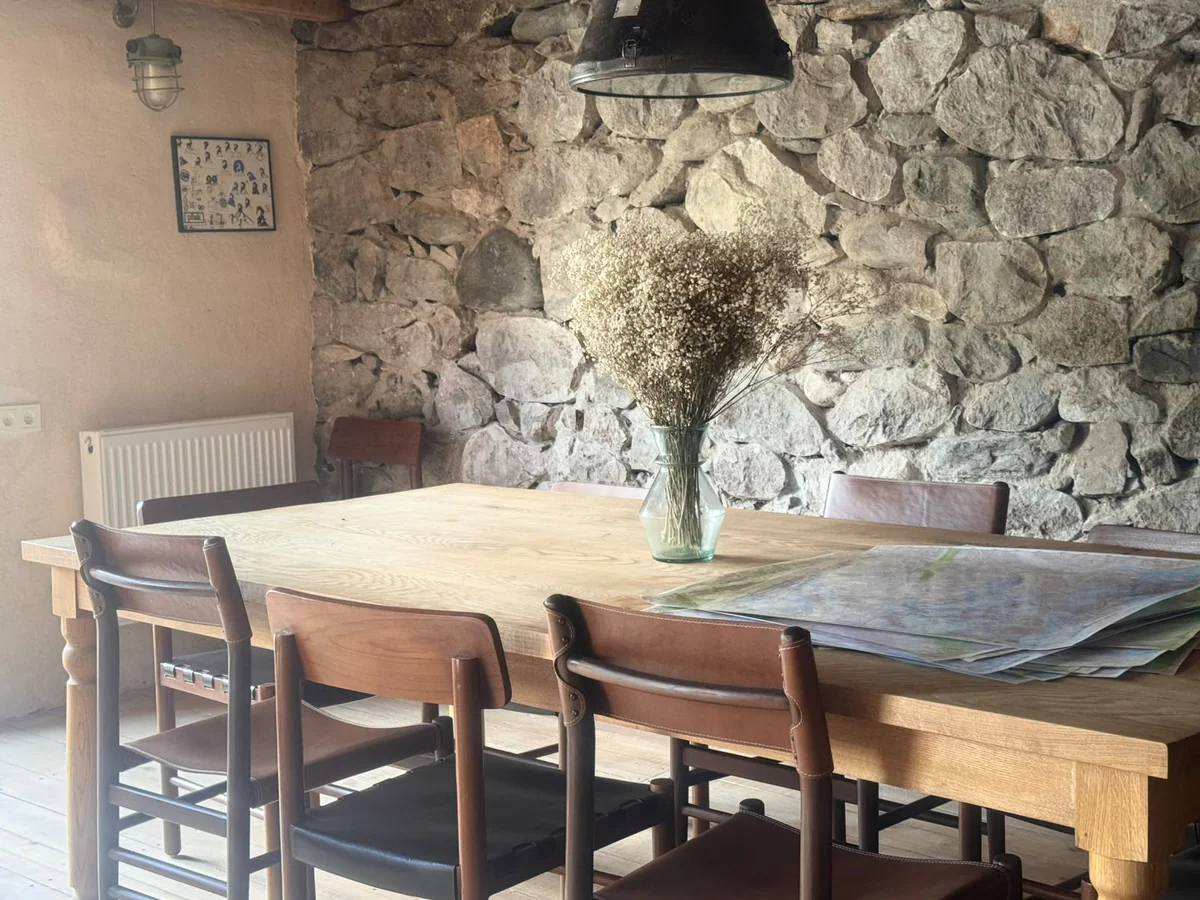 Wooden dining table with flowers in a stone-walled room