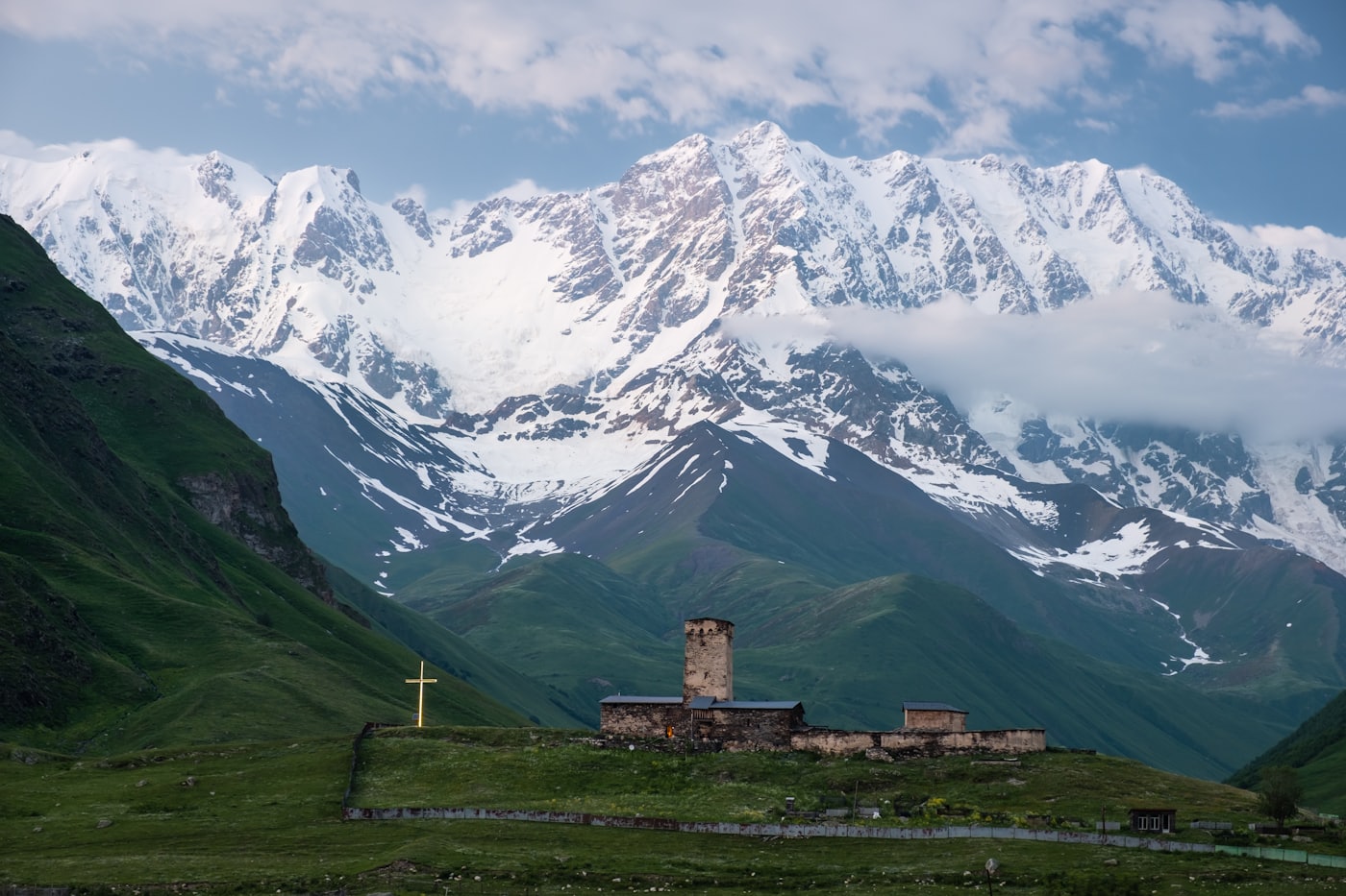Steinkirche vor dem schneebedeckten Kaukasusrücken in Swanetien